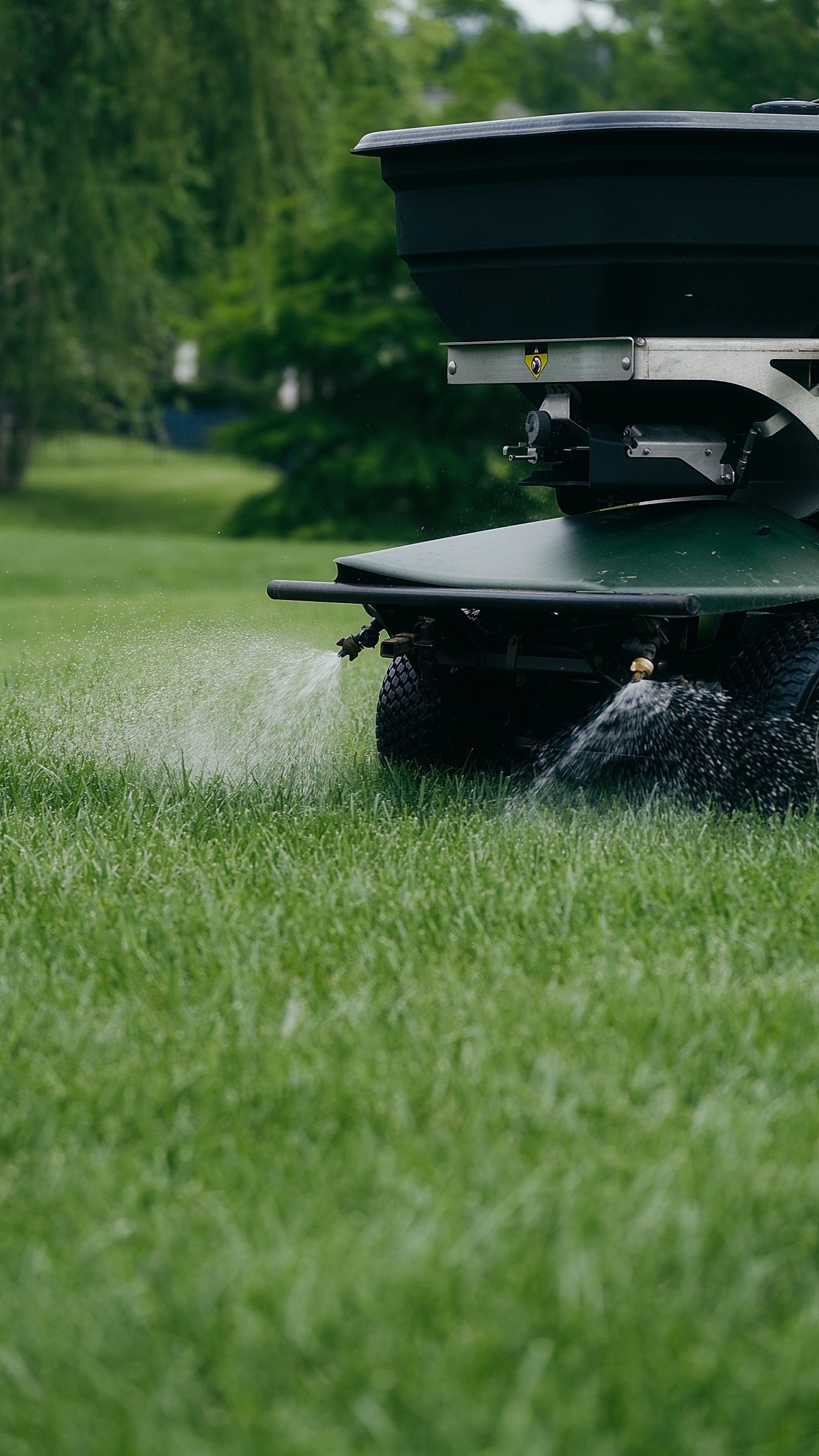 A Pure Turf spreader applying treatment across a healthy lawn, the year-round program